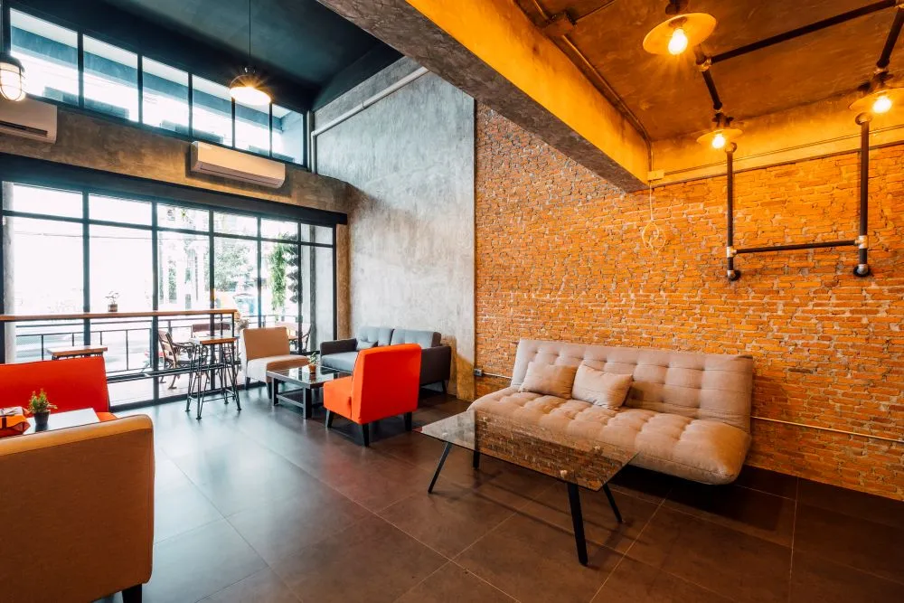 Salon esprit loft new-yorkais avec mur en briques rouges, grandes ouvertures et mobilier contemporain.